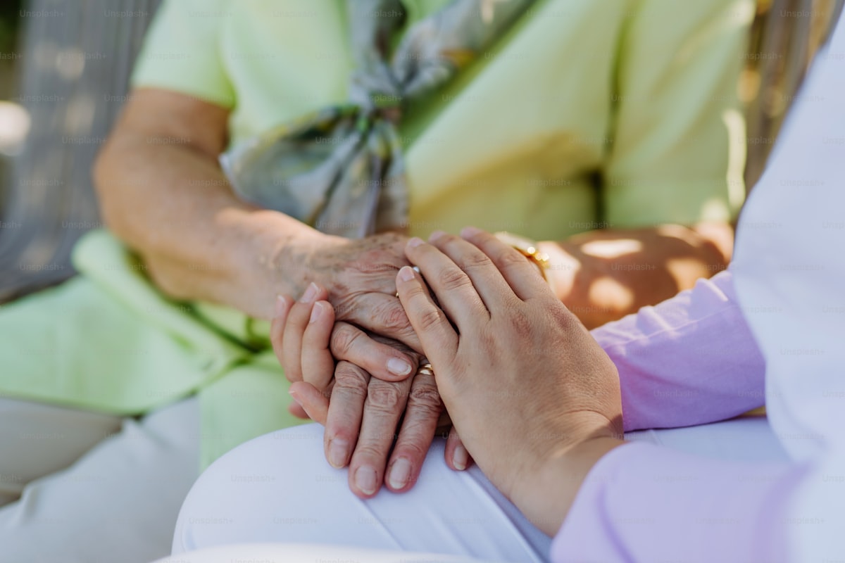 Caregiver consoling senior woman on park bench
